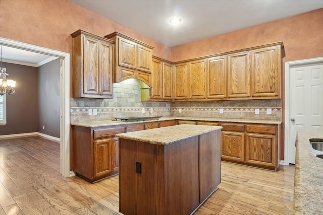 kitchen featuring light wood finished floors, tasteful backsplash, brown cabinetry, and an inviting chandelier