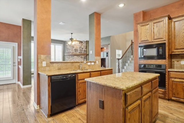 kitchen with a kitchen island, a sink, black appliances, tasteful backsplash, and light wood-type flooring