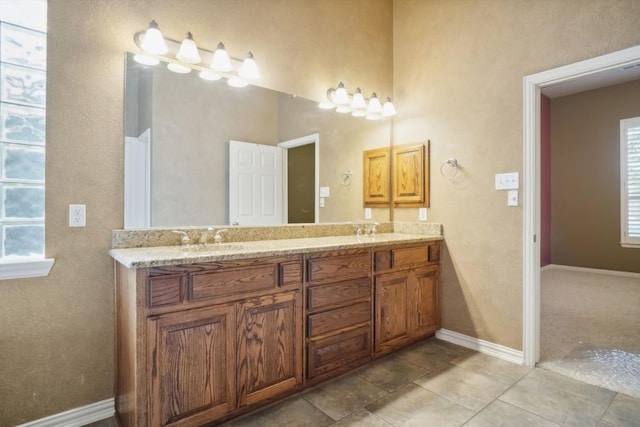 full bathroom featuring double vanity, baseboards, and a sink