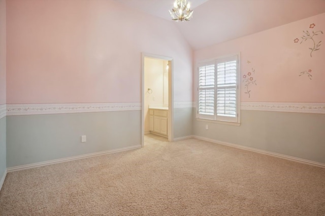 spare room featuring an inviting chandelier, lofted ceiling, light colored carpet, and baseboards