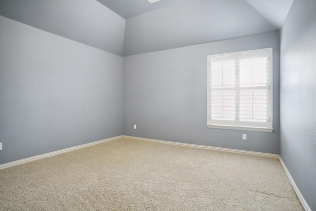 spare room featuring baseboards, lofted ceiling, and carpet flooring