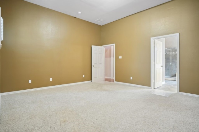 empty room featuring visible vents, baseboards, and light colored carpet