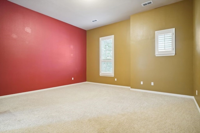 carpeted empty room featuring a wealth of natural light, visible vents, and baseboards