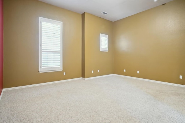 carpeted empty room featuring visible vents and baseboards