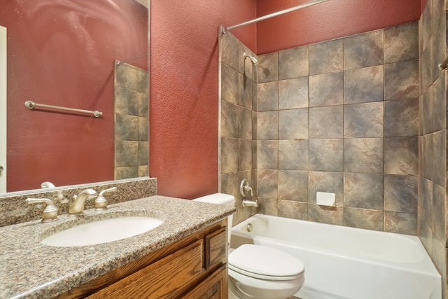 full bath with toilet, washtub / shower combination, vanity, and a textured wall