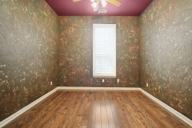 empty room with visible vents, ceiling fan, baseboards, and wood-type flooring