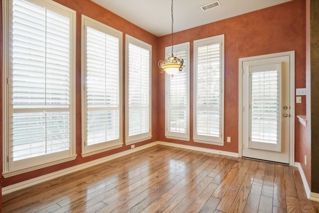 unfurnished dining area with light wood-style flooring, baseboards, and visible vents