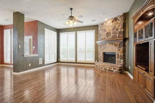 unfurnished living room featuring visible vents, a ceiling fan, wood finished floors, a fireplace, and baseboards