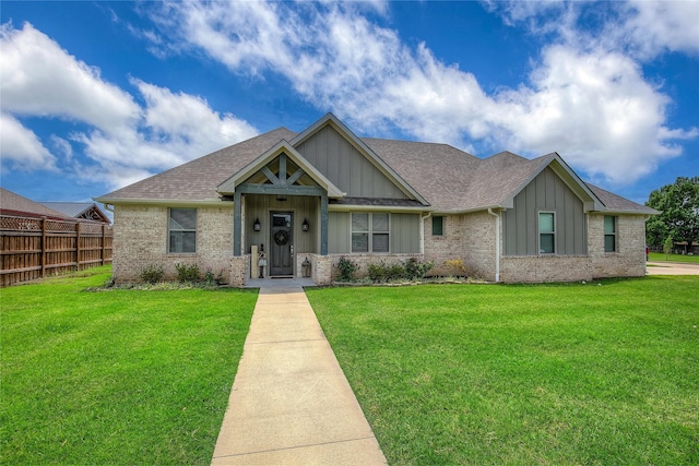 craftsman-style house with roof with shingles, board and batten siding, a front lawn, and fence