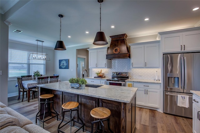 kitchen featuring visible vents, a sink, ornamental molding, stainless steel appliances, and custom range hood