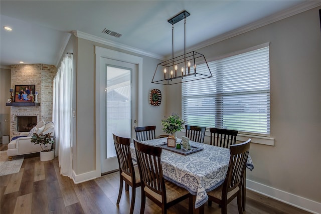 dining space featuring baseboards, visible vents, a fireplace, ornamental molding, and dark wood-type flooring