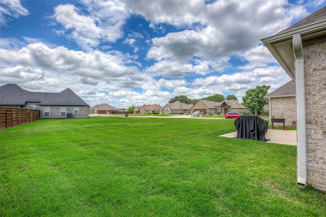 view of yard featuring a patio, fence, and a residential view