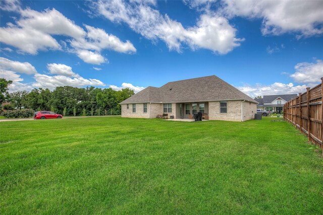 back of house with a patio, fence, roof with shingles, a lawn, and brick siding