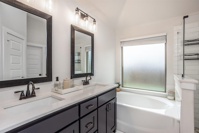 bathroom with lofted ceiling, a bath, double vanity, and a sink