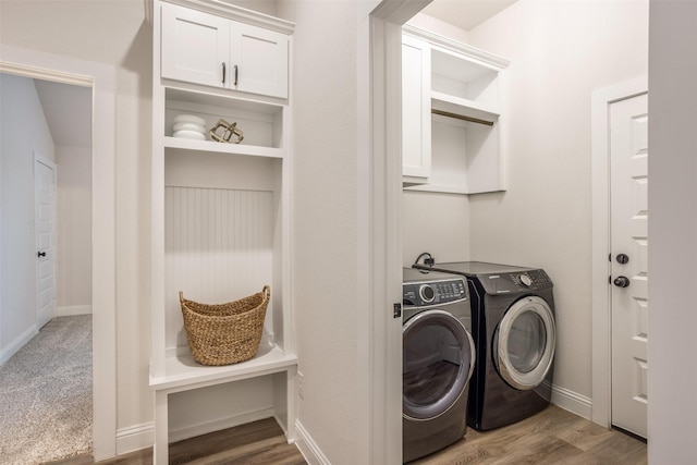 laundry area with wood finished floors, cabinet space, baseboards, and washer and clothes dryer