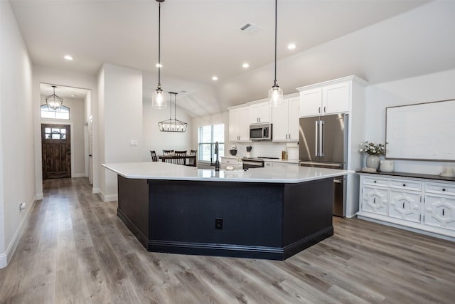 kitchen featuring visible vents, a spacious island, stainless steel appliances, light wood-style floors, and white cabinets