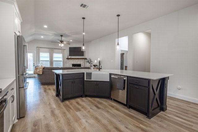 kitchen featuring visible vents, open floor plan, a stone fireplace, stainless steel appliances, and a sink