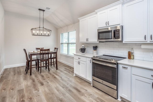 kitchen with decorative backsplash, appliances with stainless steel finishes, light countertops, and vaulted ceiling