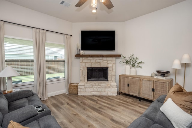 living area featuring visible vents, wood finished floors, a fireplace, baseboards, and ceiling fan