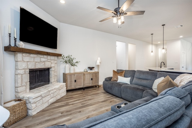 living area featuring visible vents, a stone fireplace, recessed lighting, wood finished floors, and a ceiling fan