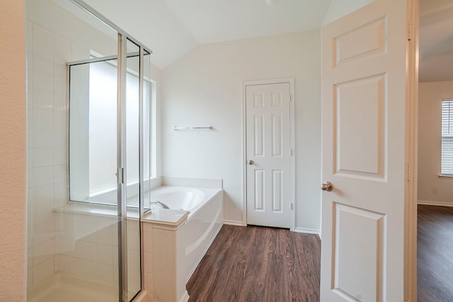 bathroom featuring a shower stall, baseboards, vaulted ceiling, wood finished floors, and a bath