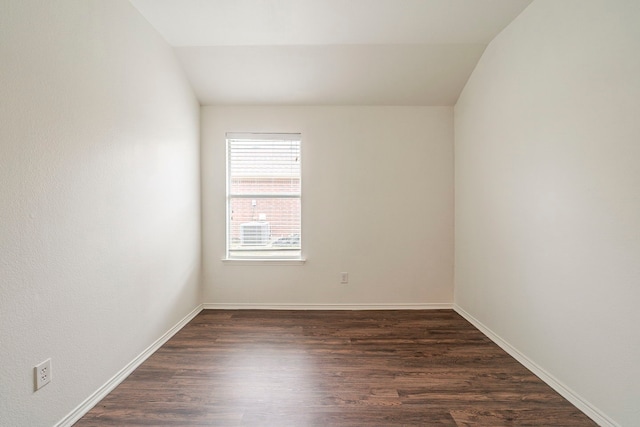 empty room featuring baseboards, dark wood-type flooring, and lofted ceiling