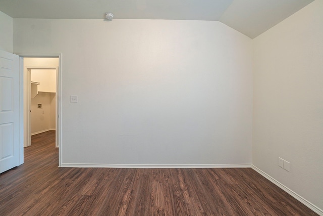 empty room featuring baseboards, dark wood-style floors, and vaulted ceiling