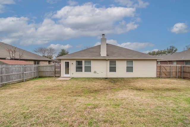 back of house with a yard, a fenced backyard, and a chimney