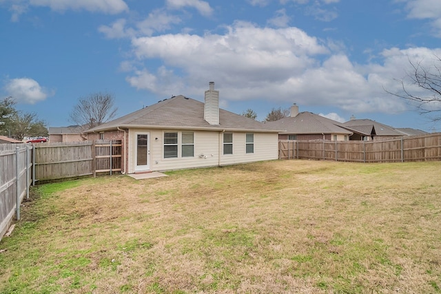 back of property featuring a lawn, a chimney, and a fenced backyard