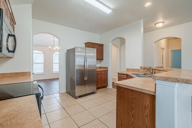 kitchen featuring a sink, light tile patterned floors, freestanding refrigerator, and black microwave