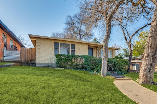 view of front of house with a front yard, fence, and brick siding