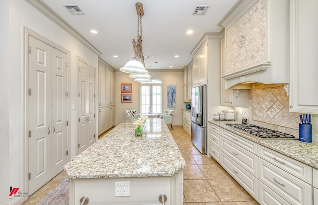 kitchen with visible vents, a kitchen island, ornamental molding, decorative backsplash, and appliances with stainless steel finishes