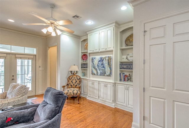 interior space featuring built in shelves, visible vents, light wood-style flooring, ornamental molding, and french doors