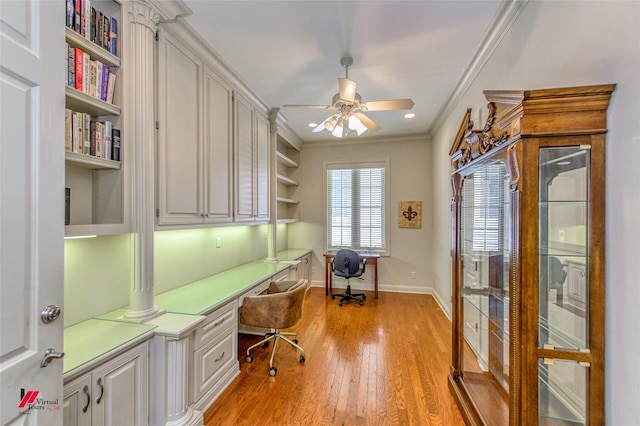 office with baseboards, light wood-type flooring, ornamental molding, built in study area, and a ceiling fan