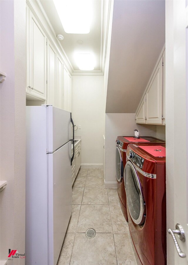 laundry area with light tile patterned floors, cabinet space, baseboards, and separate washer and dryer