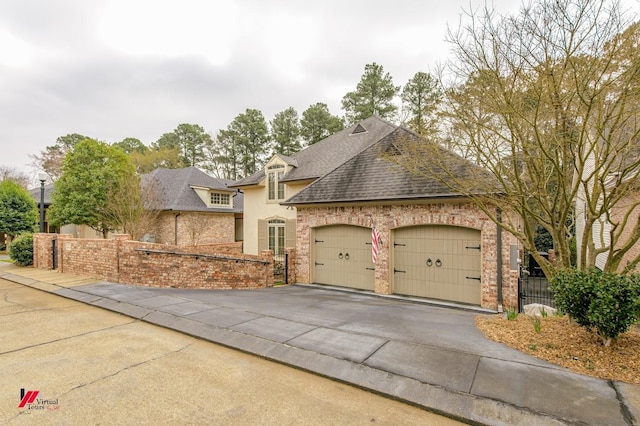 view of front of home featuring driveway, a shingled roof, a garage, and fence