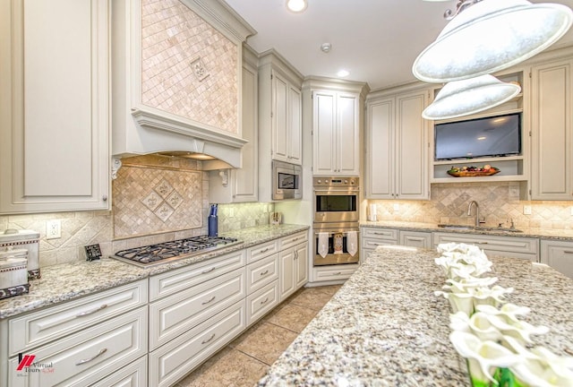 kitchen with light stone counters, light tile patterned floors, a sink, decorative backsplash, and stainless steel appliances