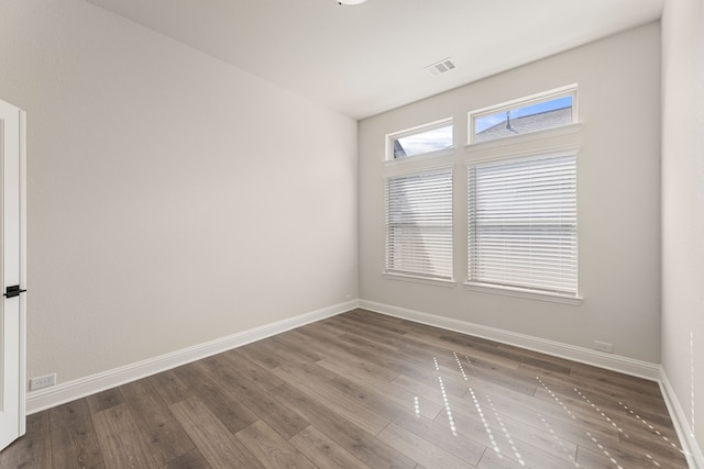 empty room featuring visible vents, baseboards, and wood finished floors