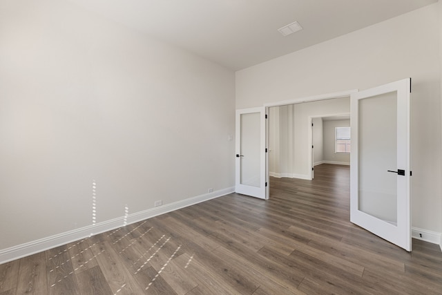 spare room featuring dark wood-type flooring and baseboards