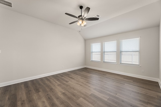 empty room with visible vents, lofted ceiling, baseboards, and dark wood-style floors