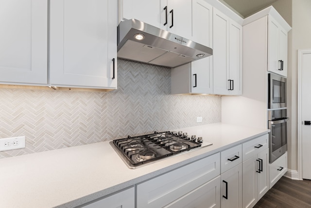 kitchen with stainless steel appliances, light countertops, white cabinets, under cabinet range hood, and backsplash