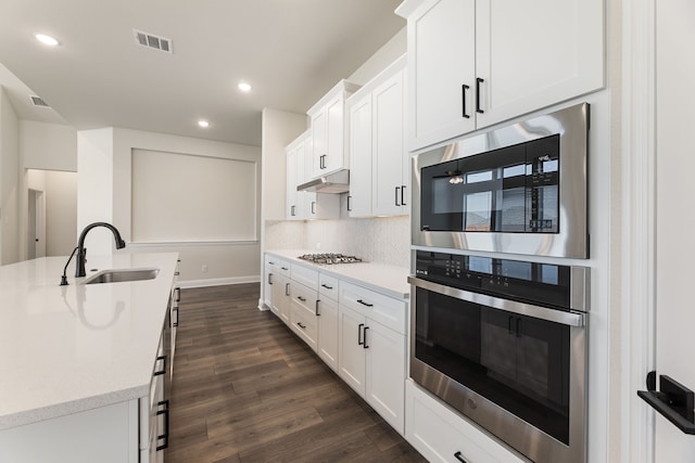 kitchen with visible vents, under cabinet range hood, appliances with stainless steel finishes, dark wood-style floors, and a sink