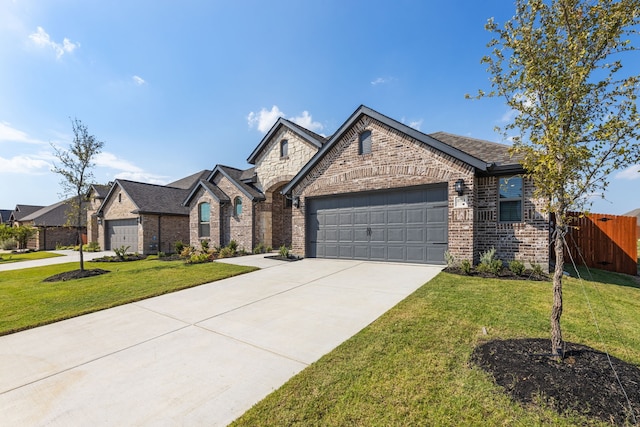 french country style house featuring fence, concrete driveway, a front yard, a garage, and brick siding