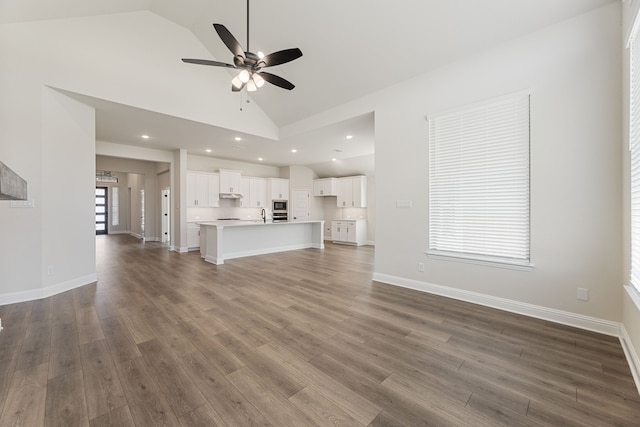 unfurnished living room featuring high vaulted ceiling, a sink, baseboards, ceiling fan, and dark wood-style flooring