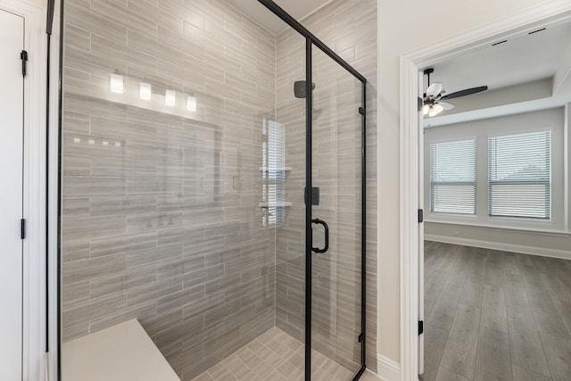 full bath featuring a ceiling fan, wood finished floors, baseboards, and a stall shower