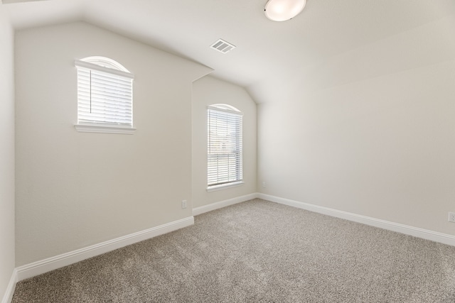 unfurnished room featuring lofted ceiling, carpet flooring, baseboards, and visible vents