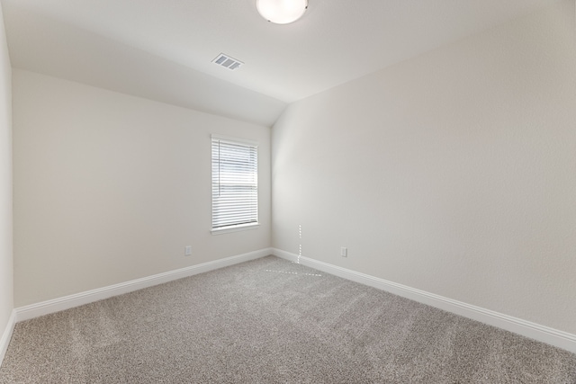 empty room featuring vaulted ceiling, visible vents, baseboards, and carpet floors