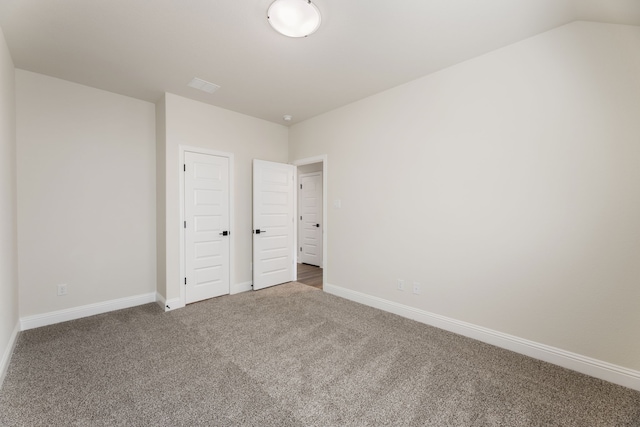 unfurnished bedroom with lofted ceiling, carpet, and baseboards