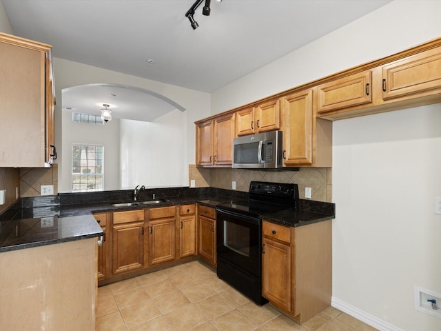 kitchen featuring tasteful backsplash, stainless steel microwave, dark stone counters, electric range, and a sink