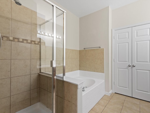 bathroom with tile patterned flooring, a shower stall, and a bath